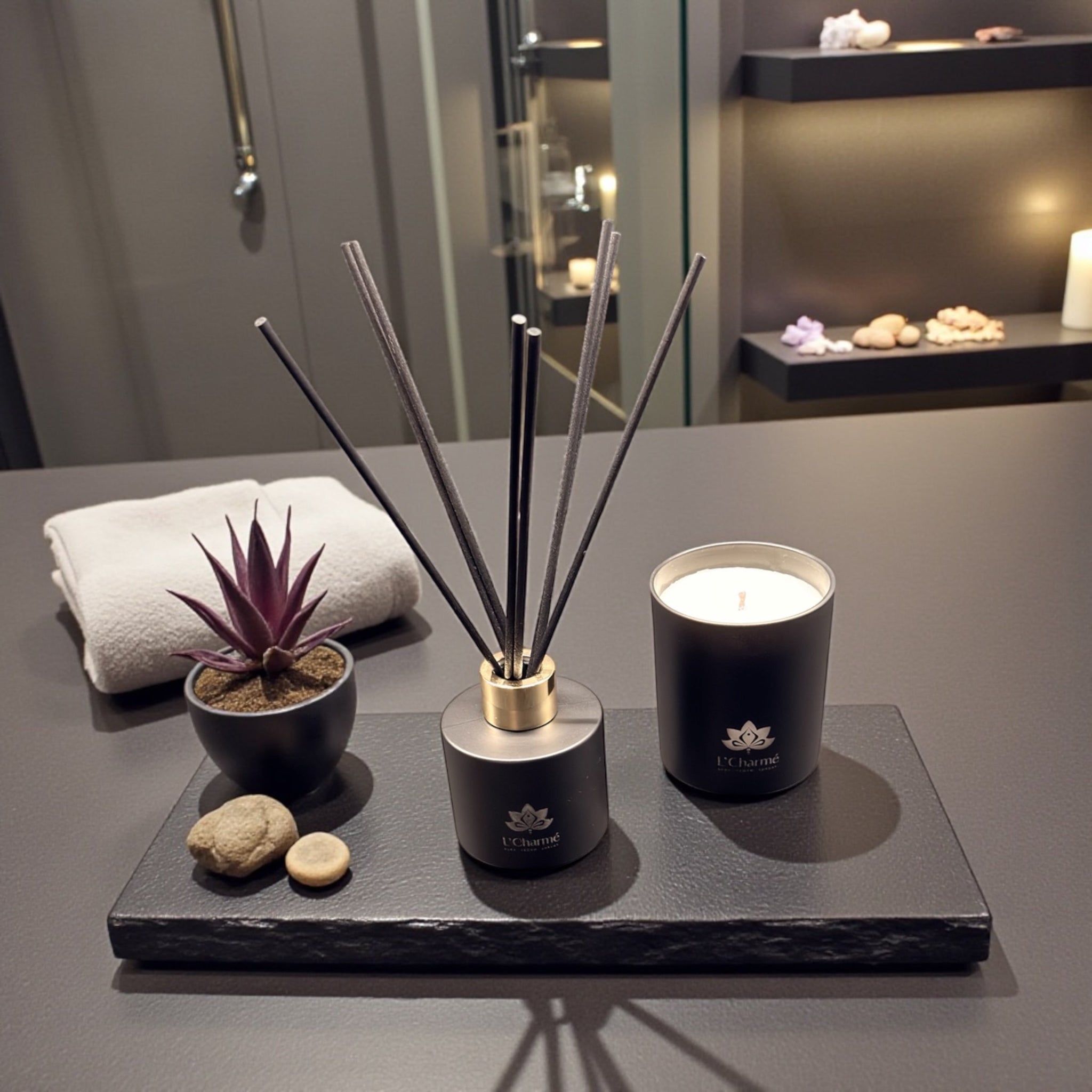 Schwarzer Duftdiffuser und Duftkerze von L’Charmé auf einer schwarzen Platte im eleganten Spa-Ambiente