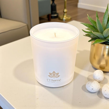 L’Charmé Duftkerze in Creme im modernen Wohnzimmer neben Sukkulente im Goldtopf.