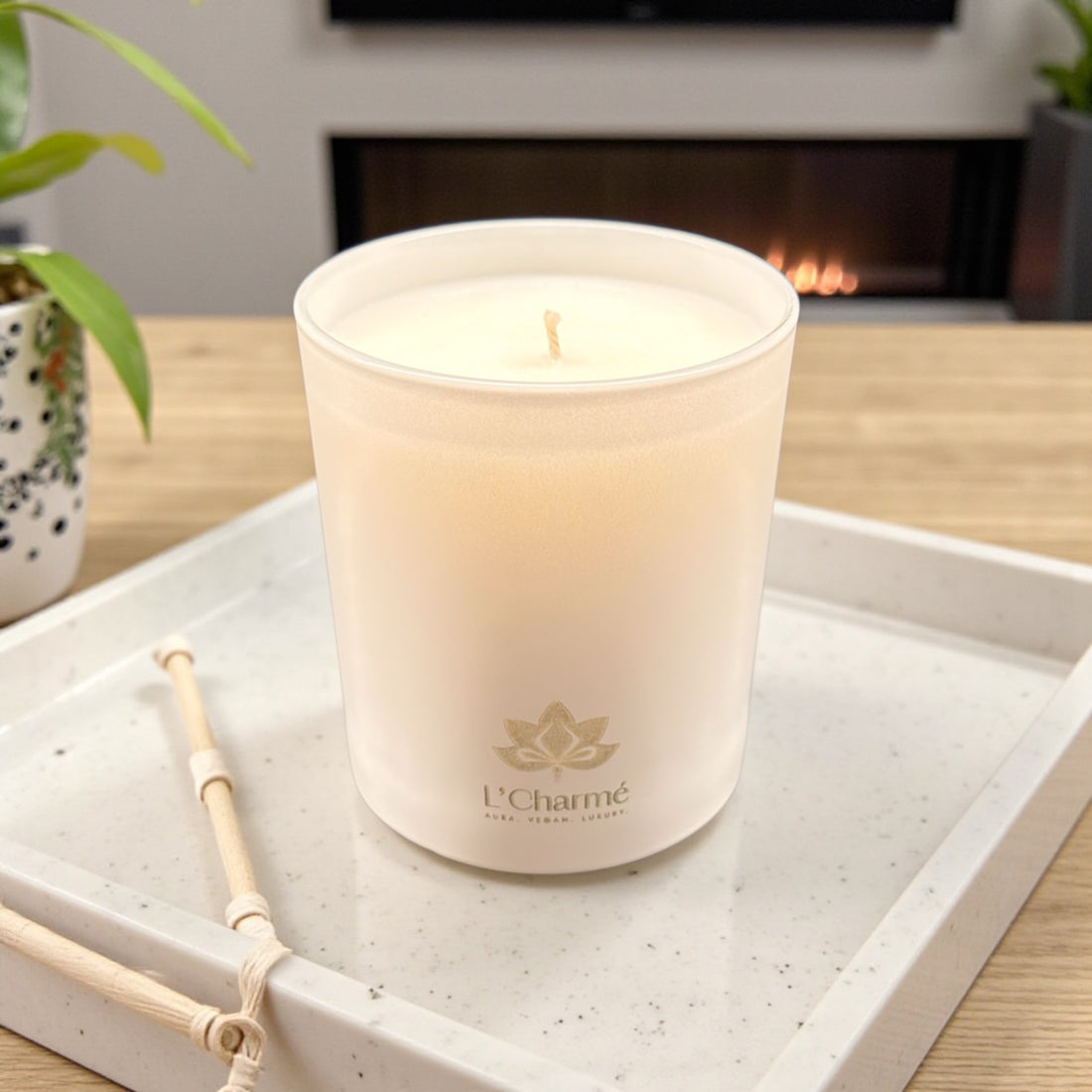 Weiße Duftkerze Lune Mystique von L’Charmé auf einem hellen Tablett vor einem Kamin in elegantem Wohnambiente