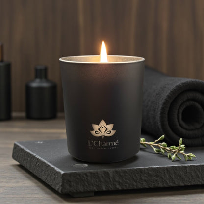 Schwarze Duftkerze von L’Charmé auf einer schwarzen Steinplatte im eleganten Spa-Ambiente