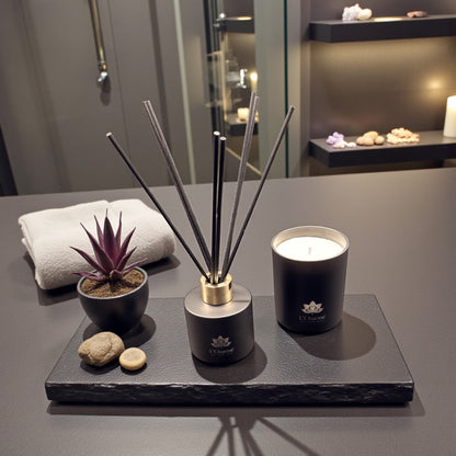 Schwarzer Duftdiffuser und Duftkerze von L’Charmé auf einer schwarzen Platte im eleganten Spa-Ambiente