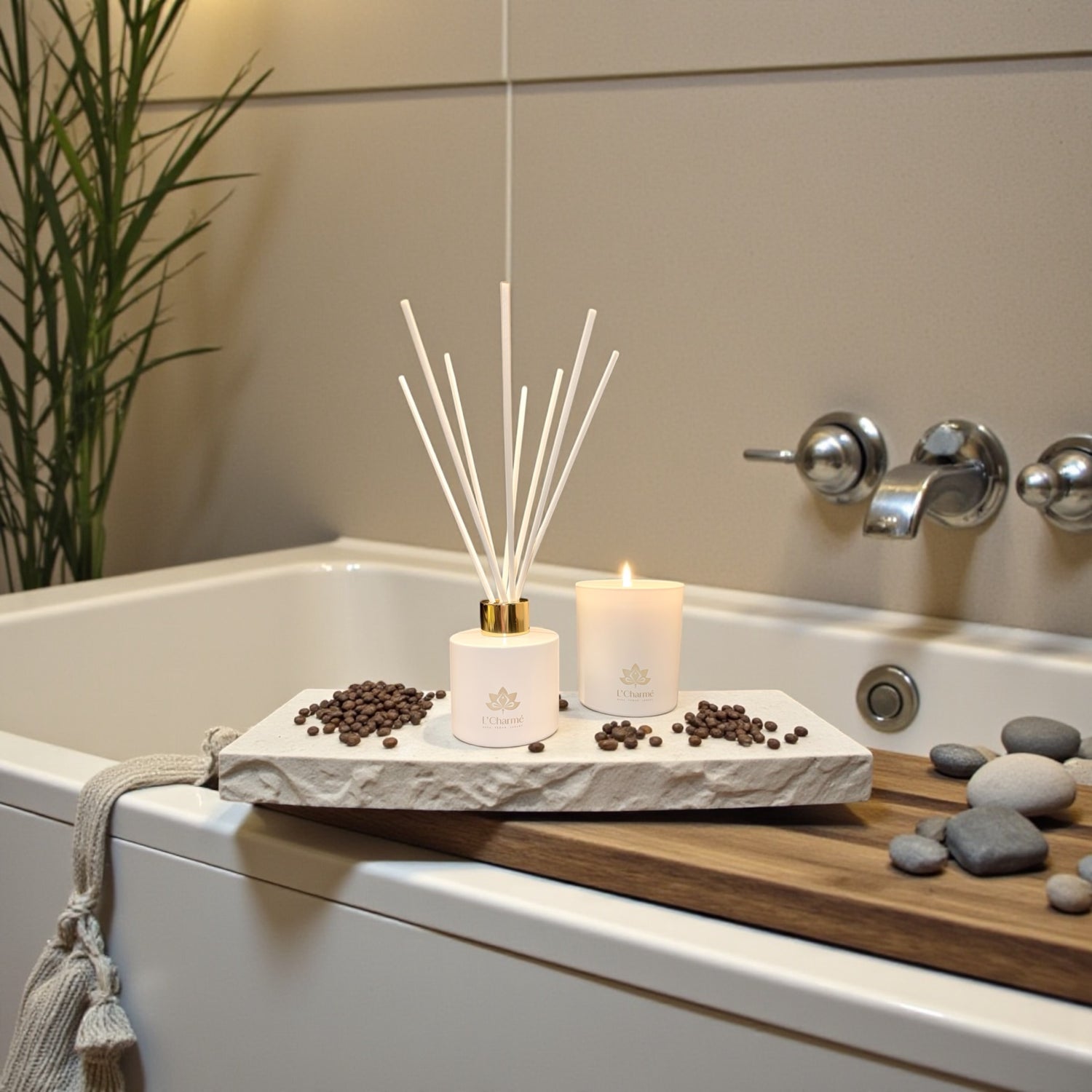 Weißer Duftdiffuser und brennende Duftkerze von L’Charmé auf einer Steinplatte an der Badewanne in ruhigem Spa-Ambiente